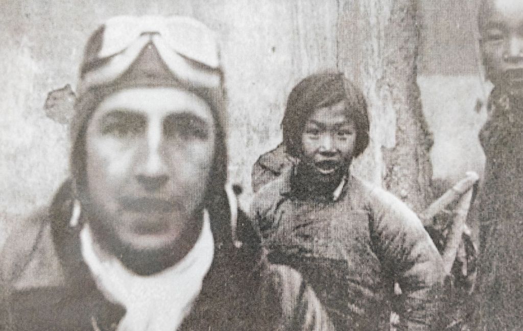 这是1942年4月，在江西上饶市广丰区，9岁的小女孩官冬香（中）站在美国飞行员身后。